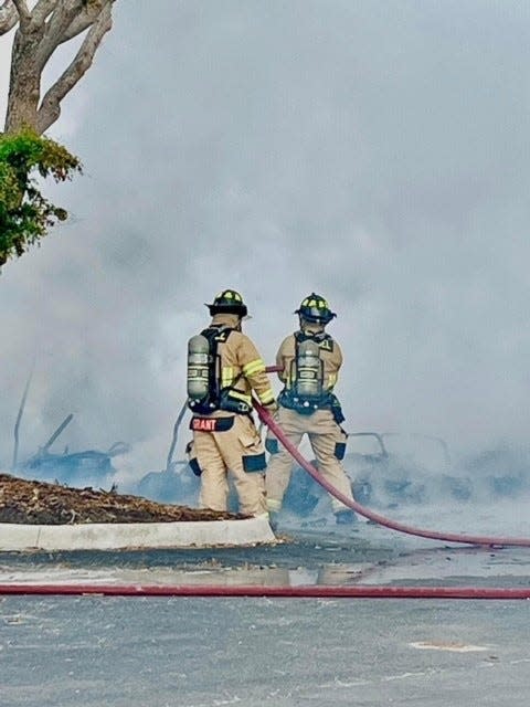 A wall of smoke can be seen in front of two firefighters from the Sanibel Fire Rescue District on Friday, Nov. 18, 2022. The smoke was caused by a fire that engulfed the golf carts at the club.