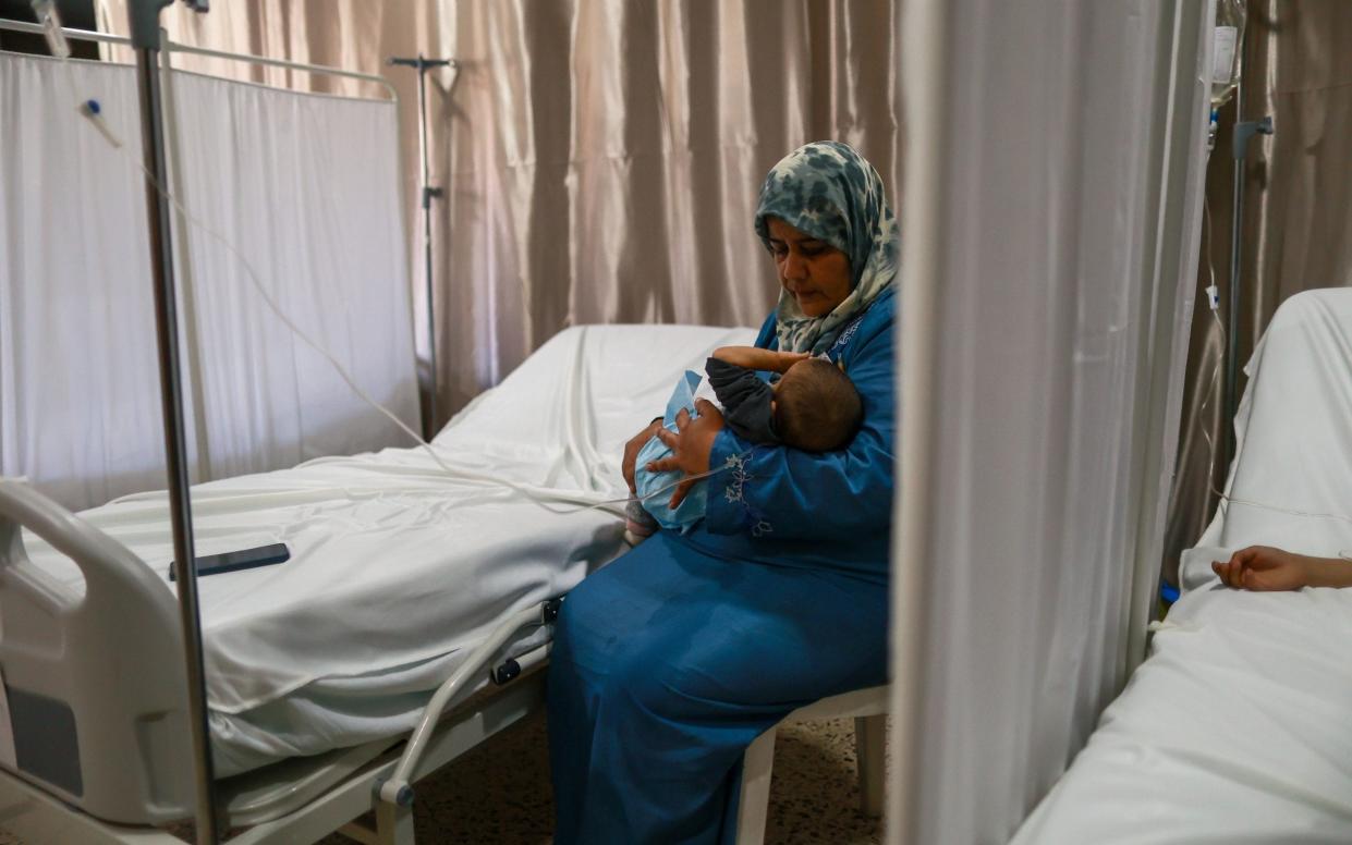 Syrian Soraya Al Hassan Al Ali holds her two-year-old son Abdallah in the field hospital set up for the cholera outbreak in Bebnine - ELISA ODDONE