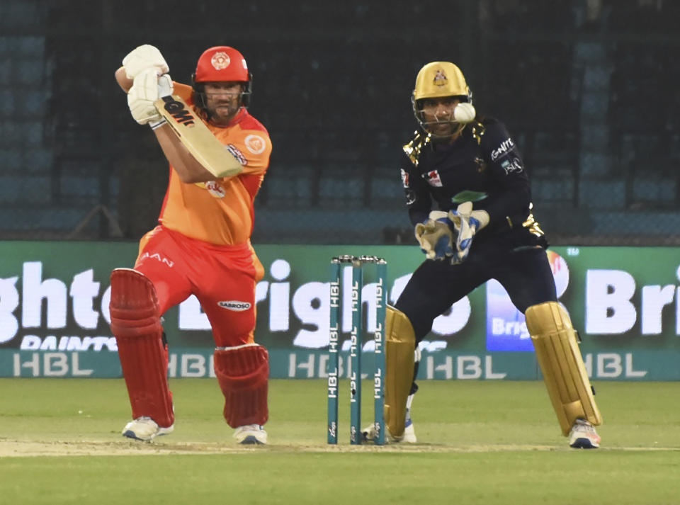 Quetta Gladiators batsman Dawid Milan hits a boundary as Islamabad United wicketkeeper Sarfaraz Ahmed looks on during the Super League opening match at National Stadium in Karachi, Pakistan, Thursday, Feb. 20, 2020. (AP Photo/Fareed Khan)