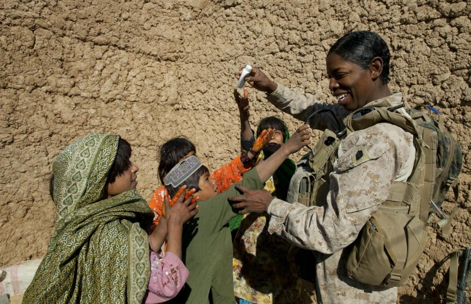 BOLDOC, AFGHANISTAN - NOVEMBER 23: (SPAIN OUT, FRANCE OUT, AFP OUT) Master Sargent Cherelle Peters-Williams, US Marine with the FET (Female Engagement Team) 1st Battalion 8th Marines, Regimental Combat team II gives out some shampoo as Afghan children grab for the goodies during a village medical outreach on November 23, 2010 in Boldoc, in Helmand province , Afghanistan. There are 48 women presently working along the volatile front lines of the war in Afghanistan deployed as the second Female Engagement team participating in a more active role, gaining access where men can't. The women, many who volunteer for the 6.5 month deployment take a 10 week course at Camp Pendleton in California where they are trained for any possible situation, including learning Afghan customs and basic Pashtun language. (Photo by Paula Bronstein/Getty Images)