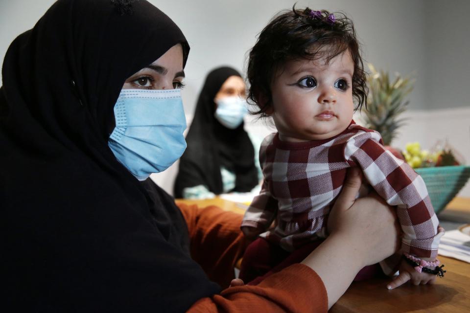 Shamila steadies 4-month -old daughter Dunya in their Beaches apartment Friday. In the background is a cousin, Monira.