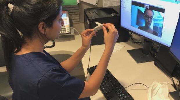 A clinician demonstrates how to use a device applied to the finger to monitor oxygen levels over a video conference at Women's College Hospital in Toronto.