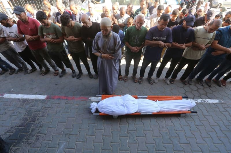 Relatives of Palestinians killed in the Israeli attacks perform funeral prayers infront their bodies ahead of their burial in Dair El-Balah. Omar Ashtawy/APA Images via ZUMA Press Wire/dpa