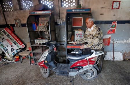 FILE PHOTO: A worker checks the power supply to recharge an electric scooter inside a workshop in Ahmedabad