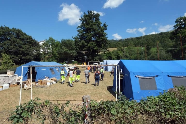 Emergency service personnel walk through a tented camp in the damaged village of Saletta, central Italy, on August 26, 2016, three days after a 6.2-magnitude earthquake struck the region