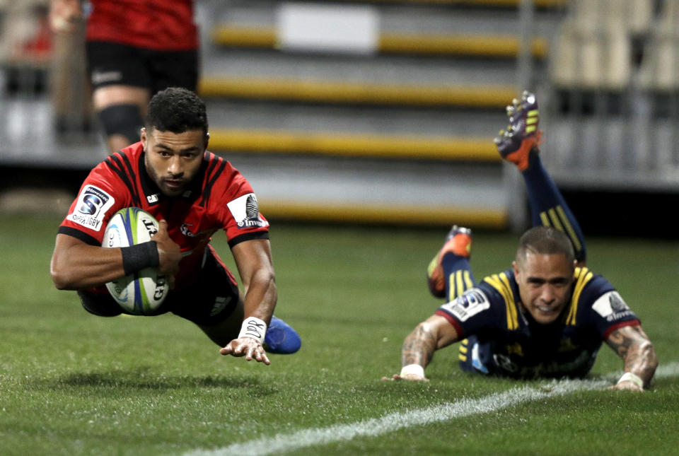 Crusaders Richie Mo'unga, left, scores his team's second try as Highlanders Aaron Smith watches during the Super Rugby quarterfinal between the Crusaders and the Highlanders in Christchurch, New Zealand, Friday, June 21, 2019. (AP Photo/Mark Baker)