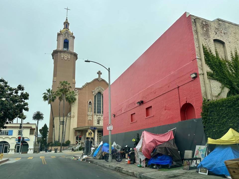 Tents line the sidewalk on Cherokee Avenue in Hollywood outside a tall building.