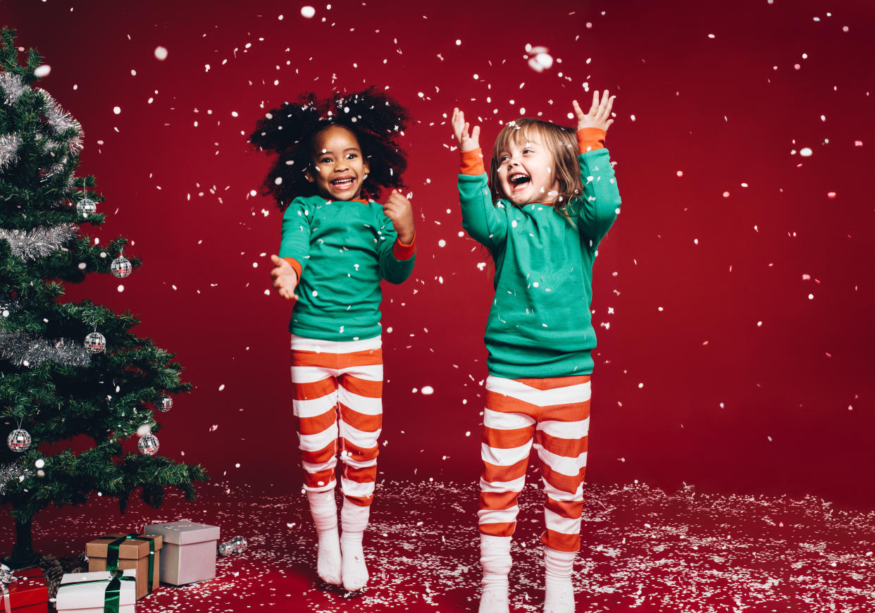 Little girls in christmas costume having fun and jumping beside a decorated christmas tree. (Posed by models, Getty Images)