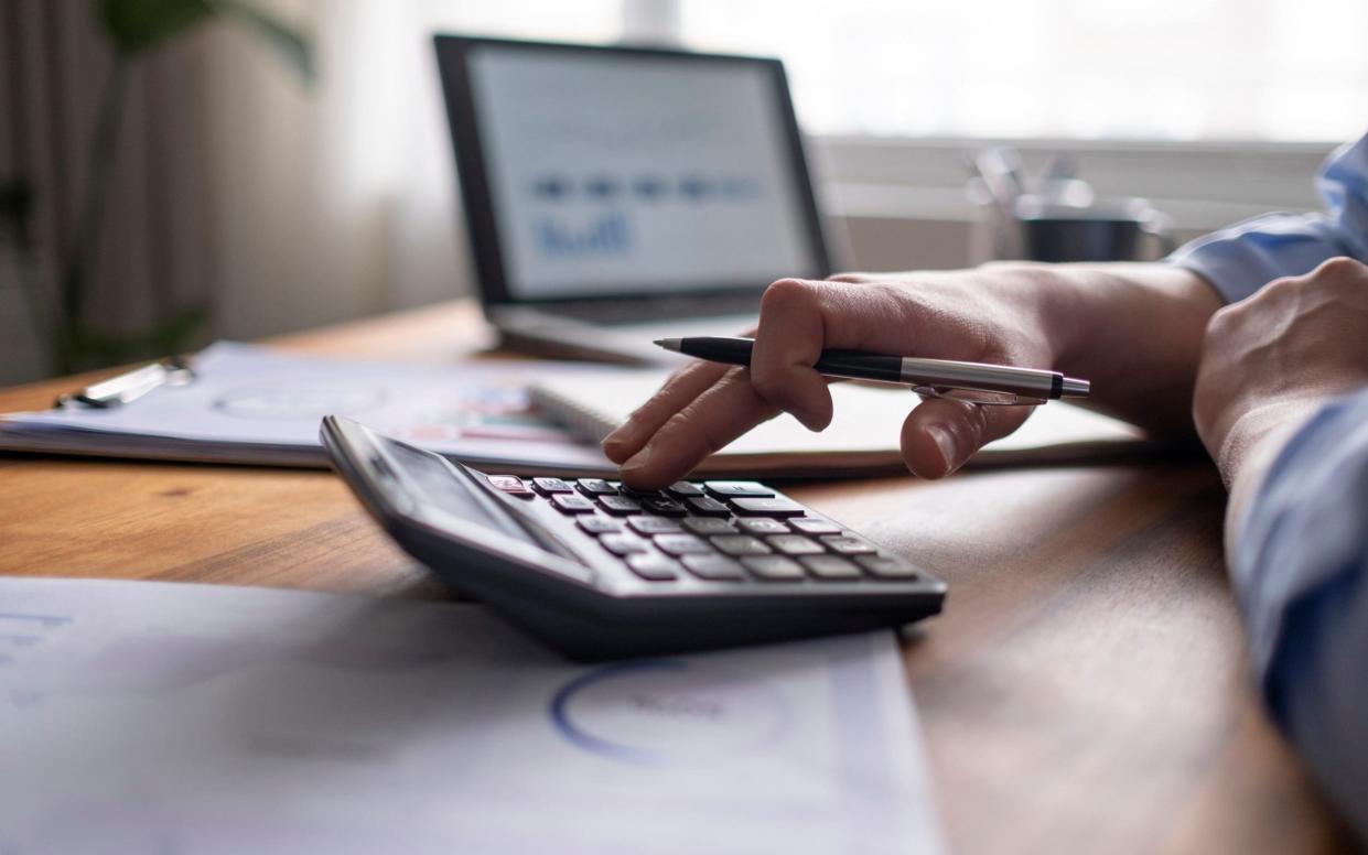 man using calculator with computer laptop looking at investment options