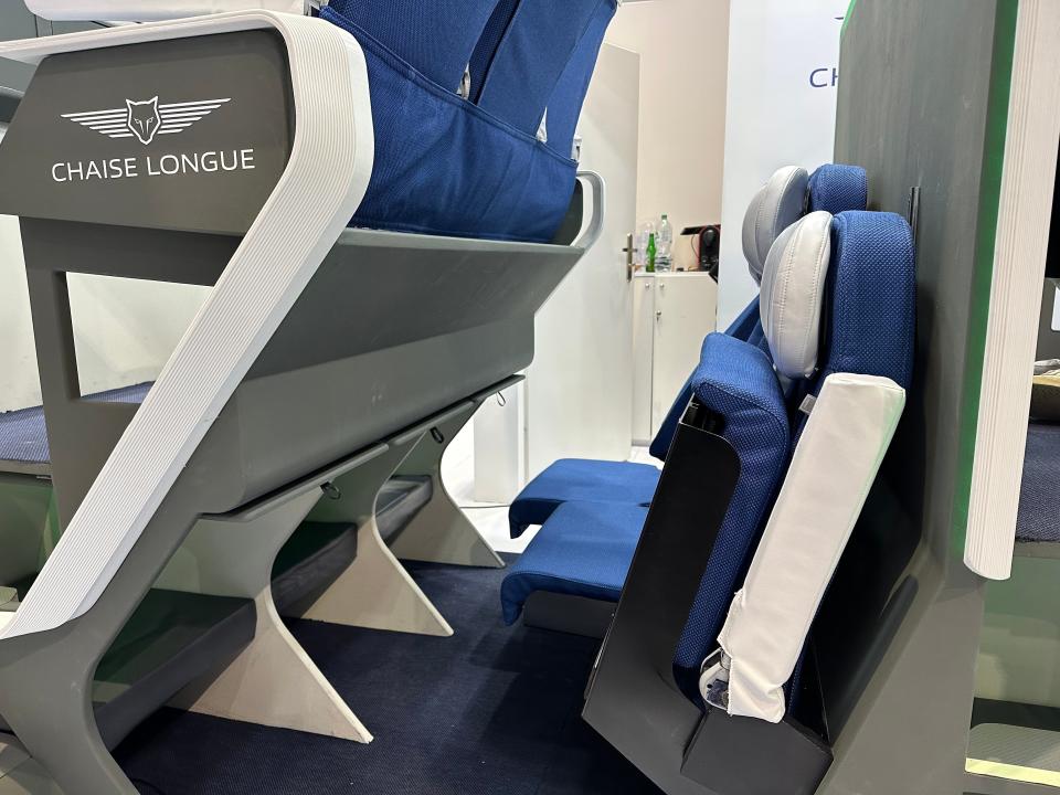 Folded up lower-level seats (foreground) and a reclined lower-level seat (background) at the Chaise Lounge Economy Seat concept display.
