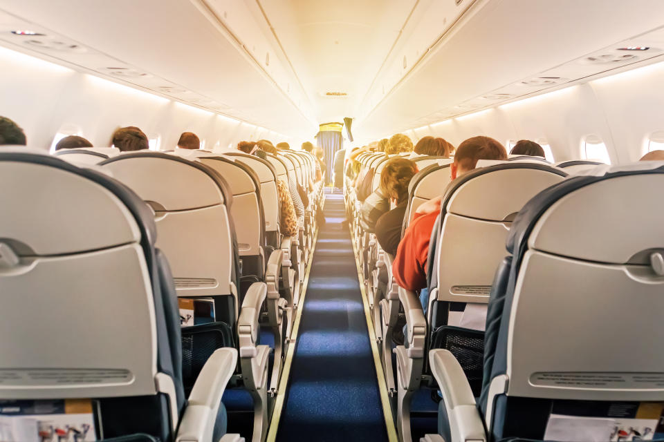 Commercial aircraft cabin with rows of seats down the aisle. morning light in the salon of the airliner. economy class