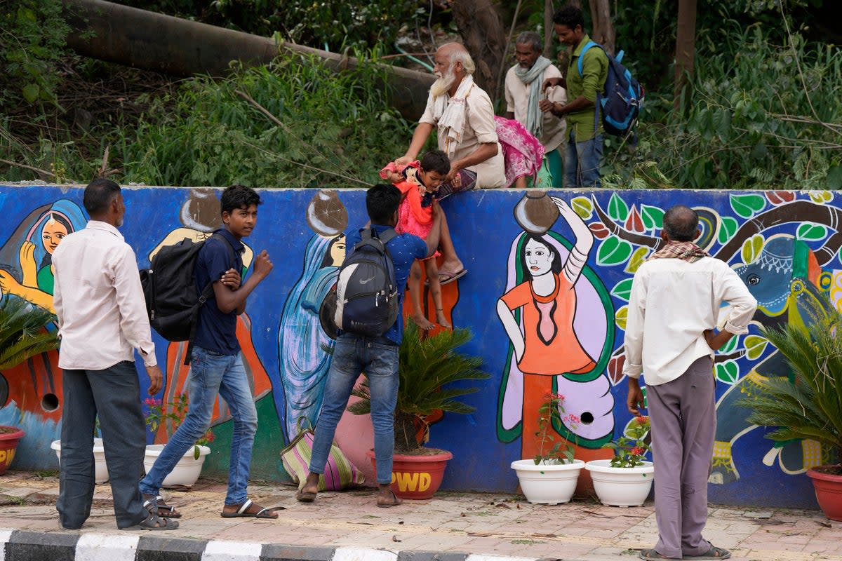 Migrant labourers climb over a wall, newly painted in preparation of the G20 summit, in New Delhi, India (AP)