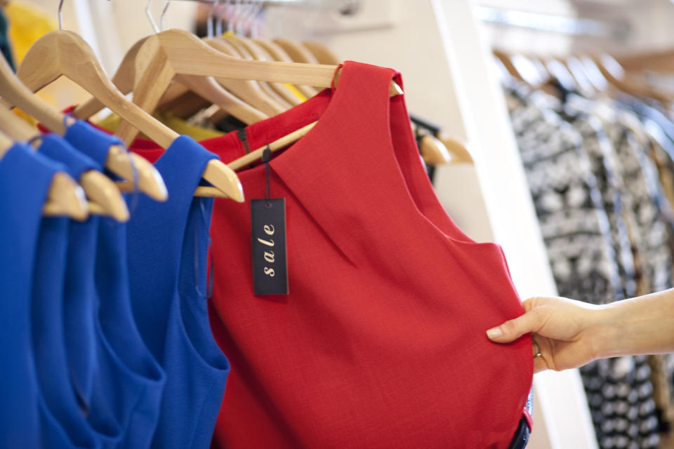 close up of a woman selecting a red dress on sale