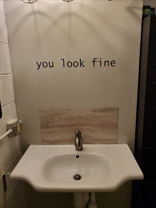 Restroom sink with a mirror above it reading "you look fine" for a confidence boost