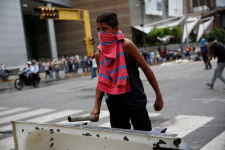 A demonstrator looks from behind a barricade as he takes part in a rally against Venezuela's President Nicolas Maduro in Caracas, Venezuela April 24, 2017. REUTERS/Carlos Garcia Rawlins