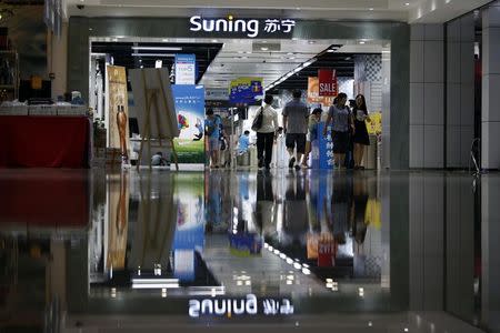 Customers walk past at the entrance to a Suning store in Shanghai, in this August 26, 2013 file picture. REUTERS/Aly Song/Files