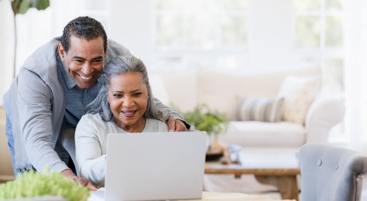 husband-to-watch-wife-shoulder-grandchildren-photos-on-laptop-SmartAsset