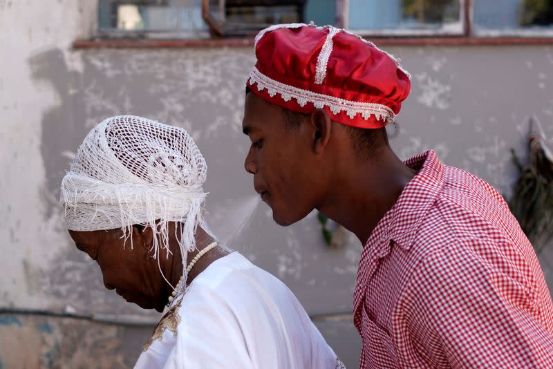 Follower of the Afro-Cuban religion Santeria spits rum during a ceremony amid concerns about the spread of the coronavirus disease outbreak in Havana