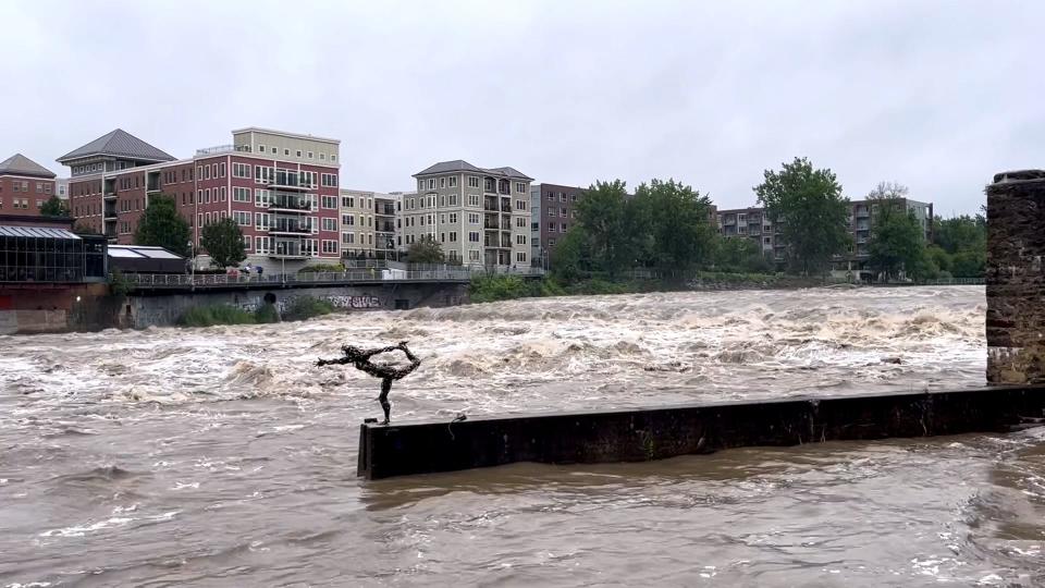 The laughing river yoga statue, standing amidst the storming Winooski River outside Burlington's Chace Mill on July 10, 2023.