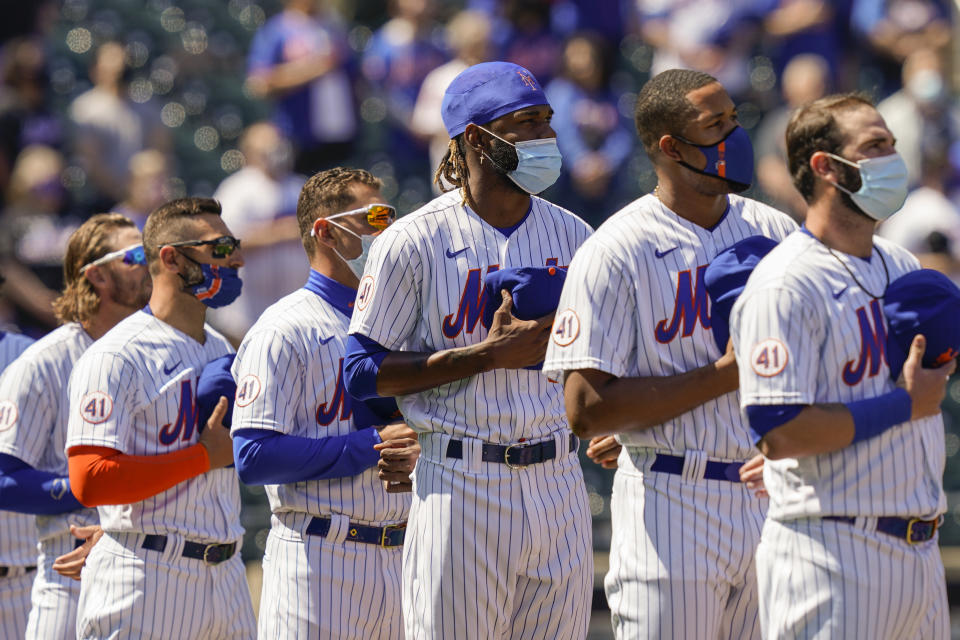 New York Mets relief pitcher Miguel Castro, center, stands for pre-game ceremonies before a home opening baseball game against the Miami Marlins, Thursday, April 8, 2021, in New York. (AP Photo/John Minchillo)