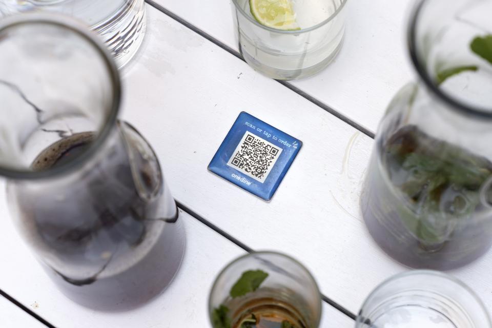 Drinks surround a barcode attached to the table at Bartaco, that patrons use to order and pay at the restaurant in Arlington, Va., on Thursday, Sept. 2, 2021. The restaurant uses an automated app for ordering and payments. Instead of servers Bartaco uses "food runners" to bring the orders to the tables. (AP Photo/Jacquelyn Martin)