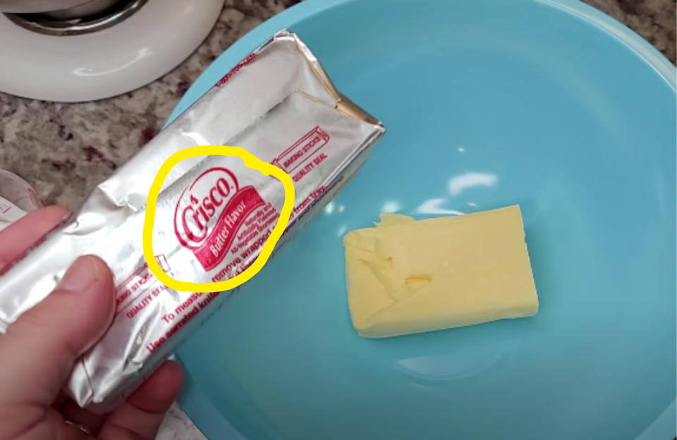 person holding crisco butter flavor shortening over a bowl for mixing cookie dough