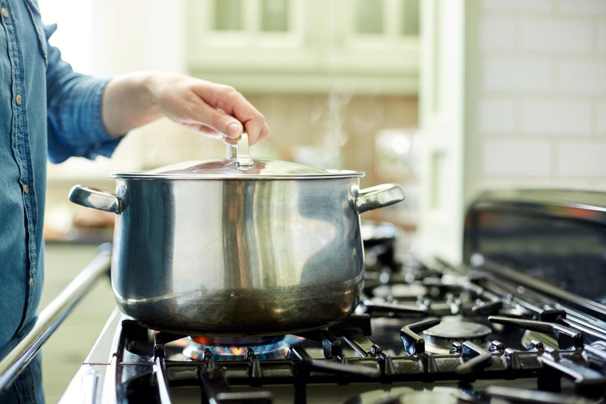 hand using lid to cover pot