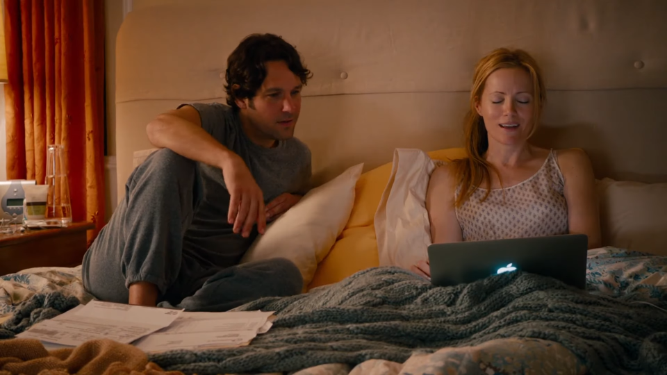 A couple sits in bed with a laptop and papers, looking concerned, in a scene from "This Is 40"
