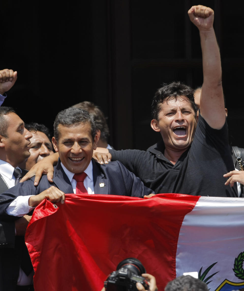 Peru's President Ollanta Humala, left, holds a Peruvian national flag during a rally celebrating the United Nations' highest court ruling on a maritime boundary between Peru and Chile, at government palace in Lima, Peru, Monday, Jan. 27, 2014. The United Nations' highest court set a maritime boundary between Chile and Peru on Monday that grants Peruvians a bigger piece of the Pacific Ocean while keeping rich coastal fishing grounds in the hands of Chilean industry. Humala, a retired army officer when he was elected Peru's president, called Monday "one of the days that will mark my life, and I feel proud to have lived as a soldier and now as a politician. I feel prouder every day to be Peruvian." (AP Photo/Juan Diego Contreras)
