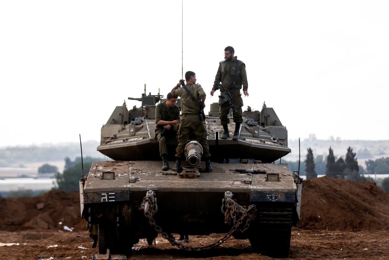 Three Israeli soldiers chat while on top of an Israeli tank near Gaza (REUTERS)