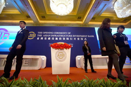 Workers walk across the stage before the opening ceremony of the Asian Infrastructure Investment Bank (AIIB) in Beijing, China, January 16, 2016. REUTERS/Mark Schiefelbein/Pool