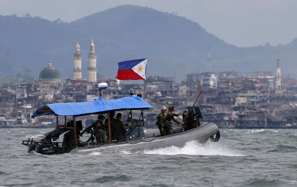 FILE - In this Oct. 19, 2017, file photo, Philippine Navy commandos aboard a gunboat patrol the periphery of Lake Lanao as smoke rises from the "Main Battle Area" where pro-Islamic group militants made a final stand amid a massive military offensive of Marawi city in southern Philippines. President Donald Trump contended this week that the United States saved the Philippines from Islamic State terrorism. His assertion vastly overstated both the threat IS posed to the country and what the U.S. did about it. (AP Photo/Bullit Marquez, File)