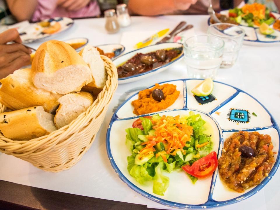 Close up of a plate of mixed Tunisian appetisers (eggplant Zaalouk, salad, fried roll, olives) in a restaurant in the old town of Tunis, Tunisia, North Africa