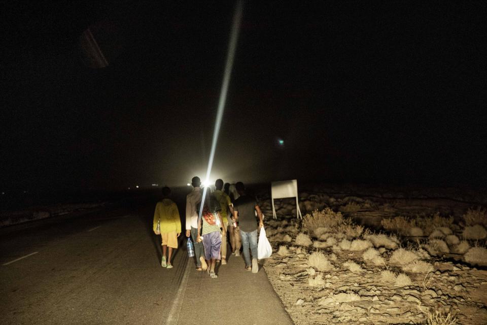 In this July 12, 2019 photo, 35-year-old Mohammed Eissa, at the front of the group, walks on a highway with boys he met on the way, around 50 kilometers (31 miles) from Djibouti. Eissa had left behind his wife, nine sons and a daughter. His wife cares for his elderly father. The children work the farm growing vegetables, but harvests are unpredictable: "If there's no rain, there's nothing." (AP Photo/Nariman El-Mofty)