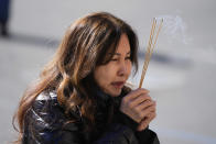 A woman is emotional as she holds incense near a memorial outside the Star Ballroom Dance Studio on Tuesday, Jan. 24, 2023, in Monterey Park, Calif. A gunman killed multiple people at the ballroom dance studio late Saturday amid Lunar New Years celebrations in the predominantly Asian American community. (AP Photo/Ashley Landis)