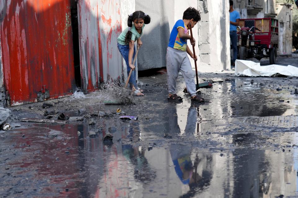Palestinian children mop outside their home after an Israeli bombardment in the Maghazi refugee camp in the Gaza Strip on Sunday, Nov. 5, 2023. (AP Photo/Hatem Moussa)