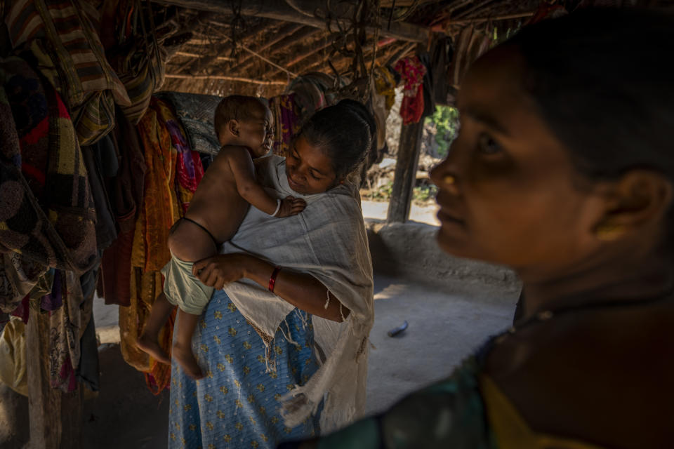 Phagni Poyam, 23, a nine months pregnant woman, dresses her one-year-old boy, Dilesh, as they get ready to shift to a health center in a motorbike ambulance in Kodoli, a remote village near Orchha in central India's Chhattisgarh state, Nov. 15, 2022. These ambulances, first deployed in 2014, reach inaccessible villages to bring pregnant women to an early referral center, a building close to the hospital where expectant mothers can stay under observation, routinely visit doctors if needed until they give birth. Since then the number of babies born in hospitals has doubled to a yearly average of about 162 births each year, from just 76 in 2014. The state has one of the highest rates of pregnancy-related deaths for mothers in India, about 1.5 times the national average, with 137 pregnancy related deaths for mothers per 100,000 births. (AP Photo/Altaf Qadri)