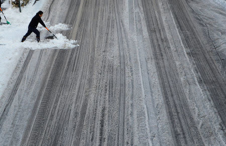 A man clears snow at a road in Tokyo, Japan, January 23, 2018. REUTERS/Kim Kyung-Hoon