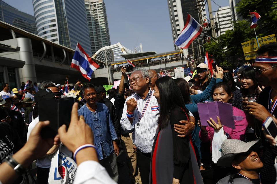 Protest leader Suthep Thaugsuban is greeted by a pregnant supporter as he leads anti-government protesters marching through Bangkok's financial district