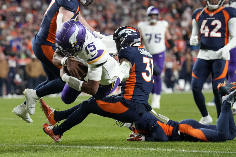 Minnesota Vikings quarterback Joshua Dobbs (15) scores a touchdown as Denver Broncos safety Justin Simmons (31) defends during the second half on an NFL football game, Sunday, Nov. 19, 2023, in Denver. (AP Photo/David Zalubowski)