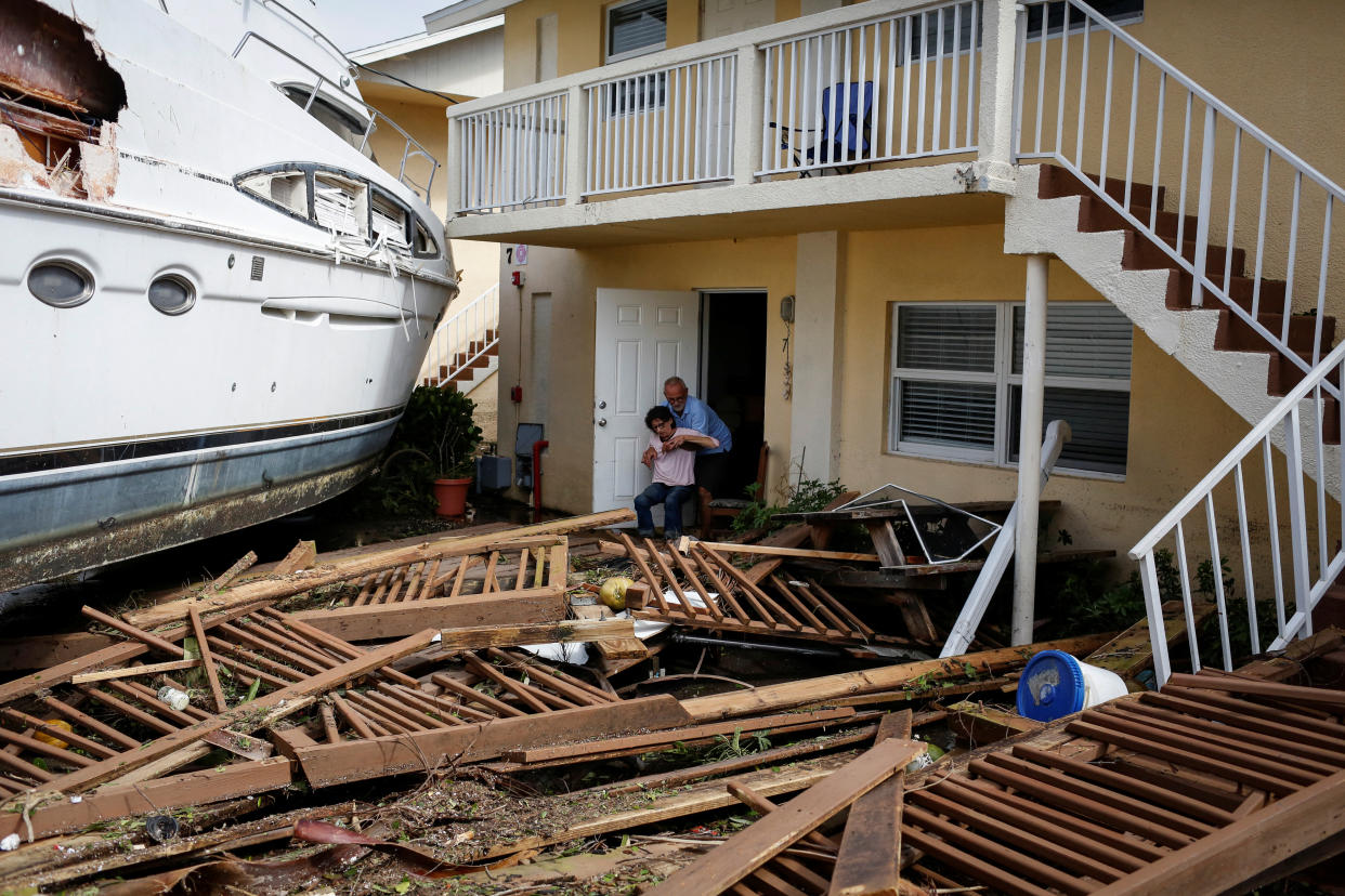 A man helps a woman next to a damaged boat in a downtown condominium after Hurricane Ian caused widespread destruction in Fort Myers.