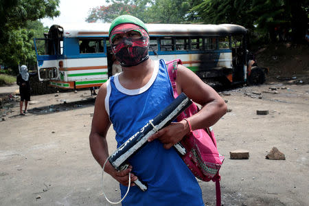 A protester stands in front of a burned bus during a protest against Nicaragua's President Daniel Ortega's government in Tipitapa, Nicaragua June 14, 2018.REUTERS/Oswaldo Rivas