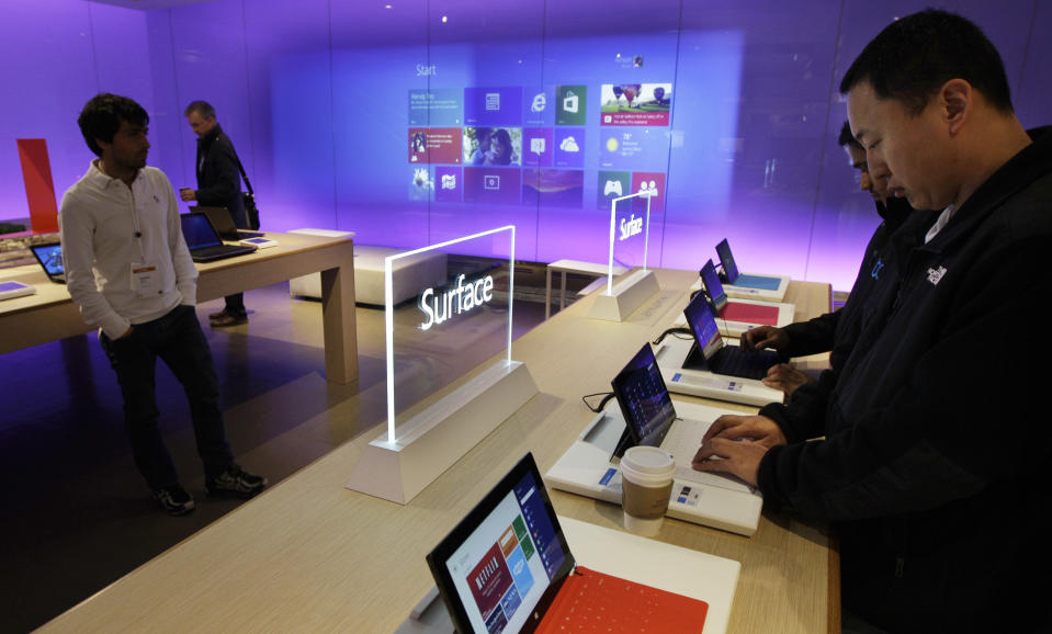 FILE - In this Wednesday, Oct. 31, 2012, file photo, visitors try out Microsoft Corp.'s "Surface" touchscreen tablet computers, at "Build," Microsoft Corp.'s developers conference, in Redmond, Wash. The Surface is Microsoft's first attempt at a general-purpose computer. In the past, it made the software and left it to other companies to make the machines. But to catch the tablet wave led by Apple's iPad, Microsoft felt it needed to make its own device. (AP Photo/Ted S. Warren, File)