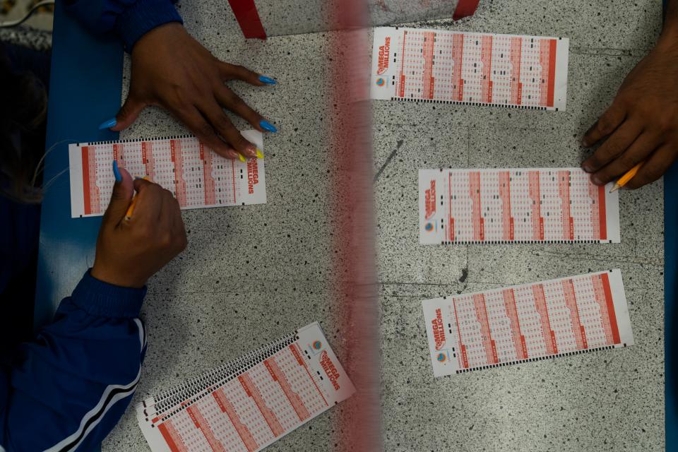 Nancy Linares, left, and Prince Joseph Israel fill out Mega Millions play slips at Blue Bird Liquor in Hawthorne, Calif., in 2022.