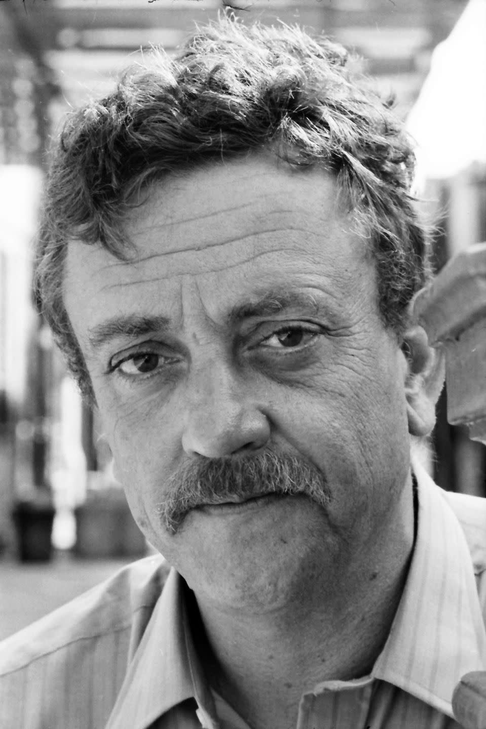 <p>Kurt Vonnegut was born and raised in Indianapolis, Indiana. He attended Cornell University, but later dropped up to join World War II. Captured by Germans during the Battle of the Bulge and interned at Dresden, he survived the Allied bombing by hiding in a meat locker of the slaughterhouse where he was being kept. After the war, he married, and published his first novel in 1952. It was not commercially successful, and though he published several novels over the 15+ years that were well regarded, it wasn’t until his sixth novel in 1969, Slaughterhouse Five, that he became a bestseller and a household name. Loosely based on his own experiences during WWII, the anti-war overtones resonated with Americans during the ongoing protests of the Vietnam War.</p>