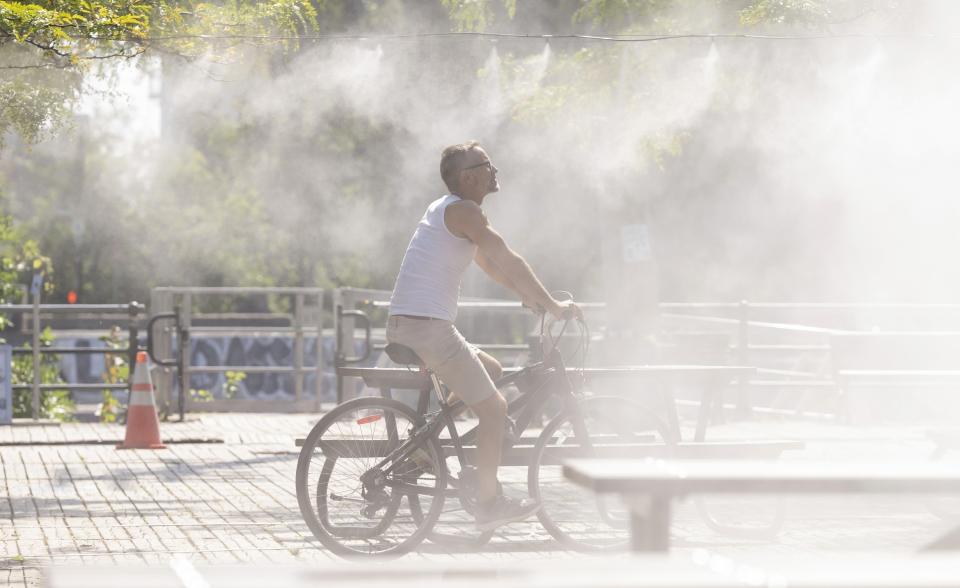 FILE - A man cycles through a mister to cool off from the heat in Montreal, Sept. 6, 2023. The latest calculations from several science agencies Friday, Jan. 12, 2024, all say that global average temperatures for 2023 shattered existing heat records. (Christinne Muschi/The Canadian Press via AP)