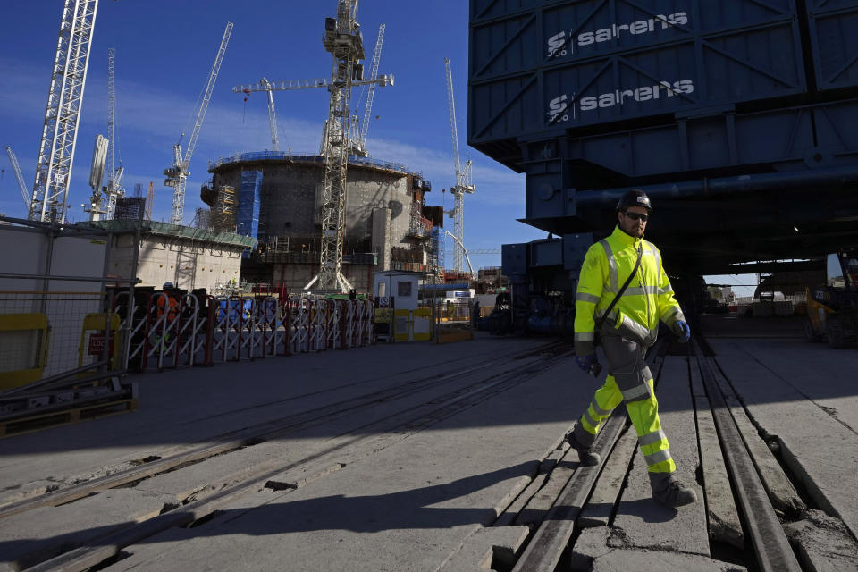 A worker walks past the construction of a nuclear reactor at Hinkley Point C nuclear power station in Somerset, England, Tuesday, Oct. 11, 2022. Hinkley Point C is set to be one of the the biggest power stations in Britain and will generate 7% of the country’s electricity. (AP Photo/Kin Cheung)