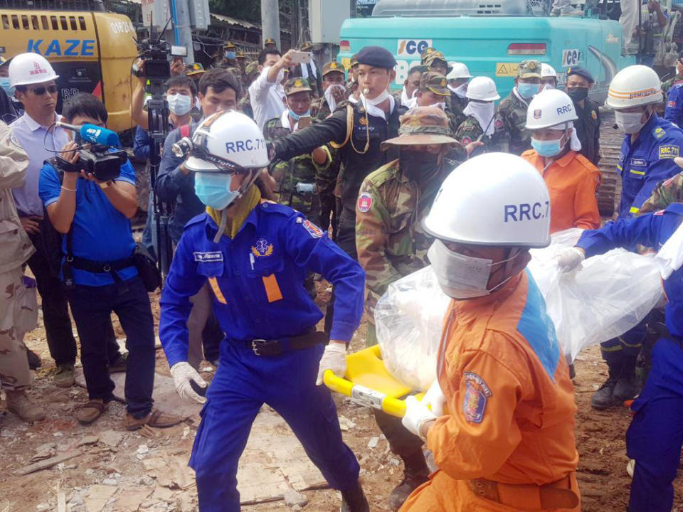 In this photo provided by Preah Sihanouk Provincial Authority, rescuers carry the body of a victim at the site of a building collapse, Monday, June 24, 2019, in Preah Sihanouk province, Cambodia. Rescuers on Monday continued to search the rubble of a building that collapsed while under construction in a Cambodian beach town, killing over two dozen workers and injuring 24 others as they slept in the unfinished condominium that was doubling as their housing. (Preah Sihanouk Provincial Authority via AP)