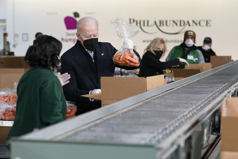 El presidente Joe Biden y la primera dama Jill Biden empacan zanahorias y manzanas el domingo en el banco de alimentos Philabundance, el 16 de enero de 2022, en Filadelfia. (AP Foto/Patrick Semansky)