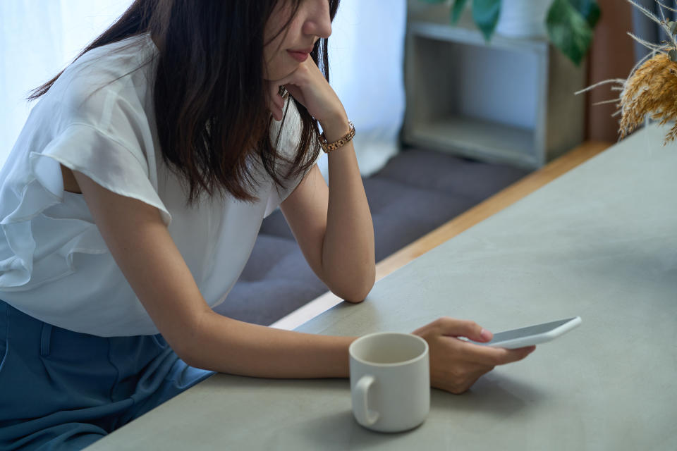 A woman staring at a smartphone with a dark expression